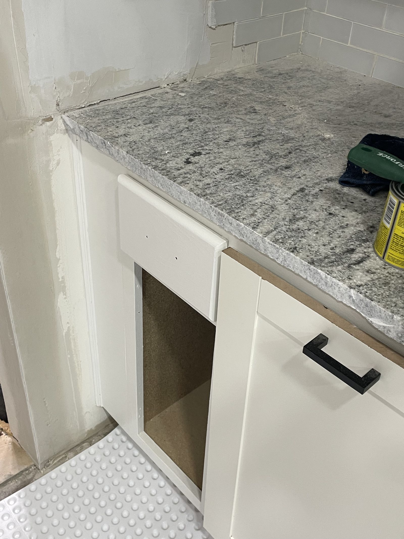 Stone counter set, backsplash tiled, hardware on — the last inch.
