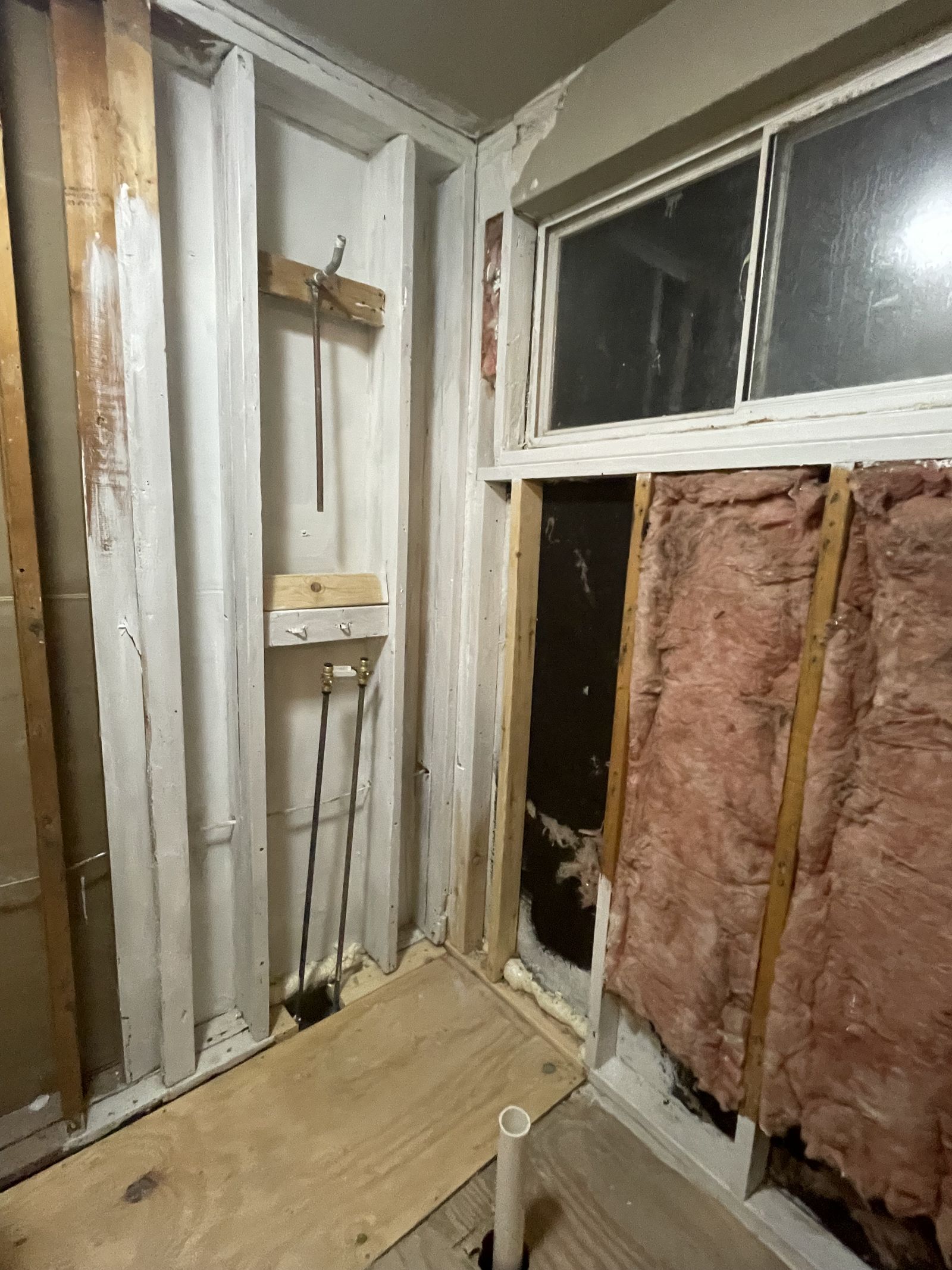Wall opened back to the studs at the Blue Room House — insulation and window header in.