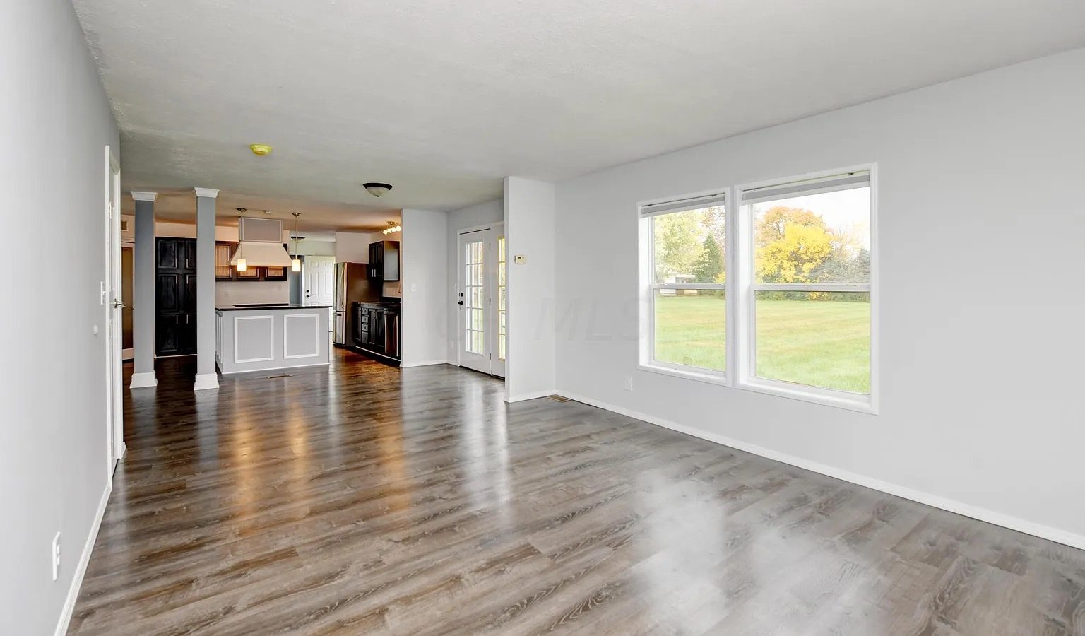 A finished, cleaned great room at handover — wainscot walls, wide-plank floors, empty and ready